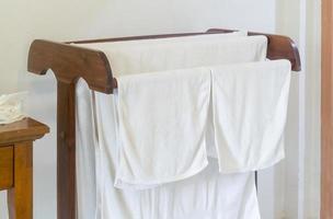 White bath towels after guest's use tidily hanging on wooden clothe line in resort or hotel room photo