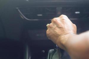 driver's hand holding automatic gear stick to shift the gear while sitting in the car driver's seat and driving luxurious super sport car. Close up photo with selective focus in vintage color tone