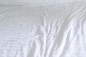 sábana blanca arrugada con patrón después del uso del huésped en la habitación del hotel con espacio para copiar. Manta desordenada textura de fondo foto