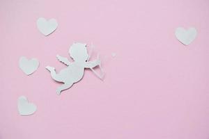 concepto del día de san valentín. corazones blancos y cupido apuntando en el corazón sobre fondo rosa. tarjetas del día de san valentín. foto