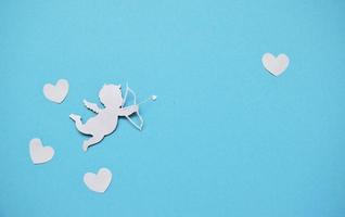 concepto del día de san valentín. corazones blancos y cupido apuntando en el corazón sobre fondo azul. tarjetas del día de san valentín. foto