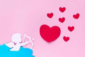 valentines day consept. red hearts and cupid aiming in heart on pink background. valentine's day card. photo