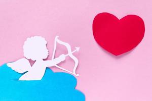 valentines day consept. red hearts and cupid aiming in heart on pink background. creative valentine's day card. photo