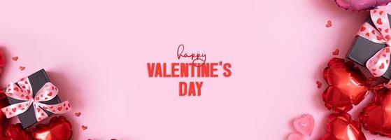 Happy Valentines Day text on greeting card. Banner with gift box with bow and heart shape baloons on pink background photo