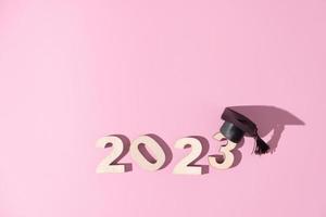 Class of 2023 concept. Numbers 2023 with black graduated cap on colored background photo