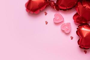 Valentines Day background with copy space and two candels with red heart shape balloons on pink background photo
