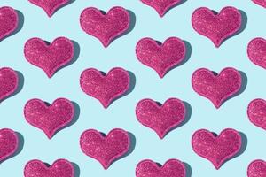 Pattern made from glitter heart shape on colored background with hard shadow. Valentines day minimalistic design photo