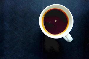 taza de café negro en la mesa negra foto