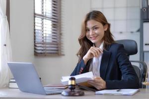 Attractive young lawyer in office Business woman and lawyers discussing contract papers with brass scale on wooden desk in office. Law, legal services, advice, Justice and real estate concept. photo