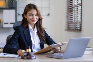 Attractive young lawyer in office Business woman and lawyers discussing contract papers with brass scale on wooden desk in office. Law, legal services, advice, Justice and real estate concept. photo