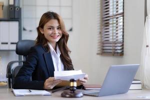 Attractive young lawyer in office Business woman and lawyers discussing contract papers with brass scale on wooden desk in office. Law, legal services, advice, Justice and real estate concept. photo