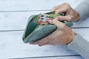 Women's hands fold or take out banknotes from a green wallet. The money is in the wallet. photo