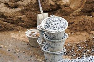 Stone buckets are stacked near the pile of sand to prepare for mixing with cement and other aggregates in the mortar mixer. soft and selective focus. photo