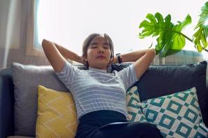 Asian woman Close your eyes and lean on the sofa. She rested her head on her interlaced hands. To rest comfortably in your leisure time. Concept relax after work, relax, cozy corner, calm corner, nap photo