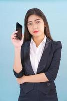 Women in suit holding smartphone against blue background photo