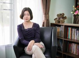 Mujer asiática joven cabello corto relajación en la sala de estar foto