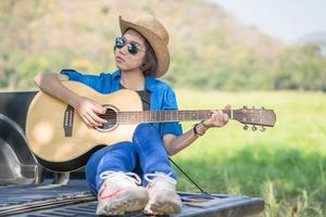 mujer usa sombrero y toca la guitarra en una camioneta foto