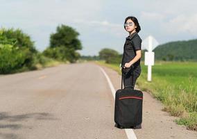 mujer con equipaje haciendo autostop por una carretera foto