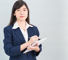 Woman in suit using digital tablet on gray background photo