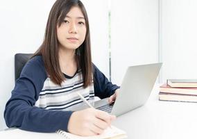 Young female student  sitting in living room and learning online photo