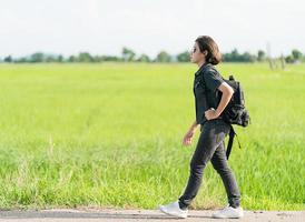 Woman with backpack hitchhiking along a road photo