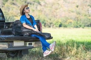 Woman wear hat and carry her guitar bag on pickup truck photo