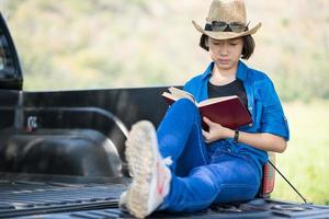 mujer usa sombrero y lee el libro en una camioneta foto