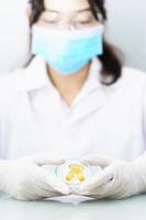 científico que sostiene la cápsula omega 3 en la bata de laboratorio foto