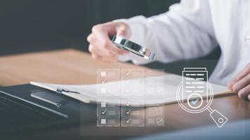 Businessman holding a magnifying glass to show audit documents, quality assessment management With a checklist, business document evaluation process, market data report analysis and consulting photo