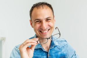 un hipster latino con gafas con los brazos cruzados y sonriendo en un fondo blanco foto