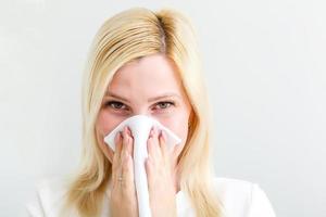 Ill woman blowing her nose in her living room photo