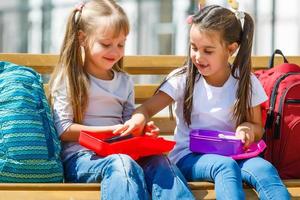 Elementary school kids sitting with packed lunches photo