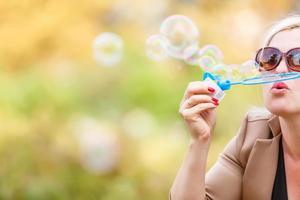 attractive young girl with soap-bubbles in beautiful yellow sunshine photo