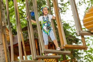 niña feliz en un parque de cuerdas en el fondo de madera foto