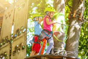 happy little children in a rope park on the wood background photo