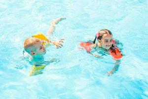 Smiling boy and little girl swimming in pool in aquapark photo