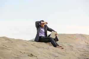 Businessman sitting alone in the empty desert photo
