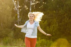 Closeup street portrait of a beautiful fashionable woman with long hair walking at sunset. Space for text. photo