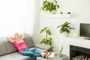 Happy young woman lying on couch and relaxing at home, casual style indoor shoot. Portrait of a girl relaxing on a sofa after work at home sitting on a sofa in the living room at home photo