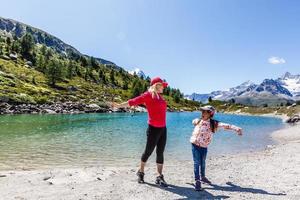 Happy hiker woman and girl at mountains lake photo