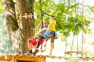 adventure climbing high wire park - children on course rope park in mountain helmet and safety equipment photo