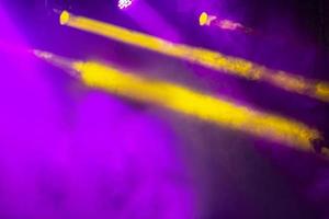 fondo del escenario del concierto de humo púrpura y rayas de luz amarillas sobre un fondo negro. foto