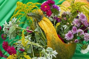 The pumpkin was cut out in the form of a vase and autumn flowers were placed there. photo