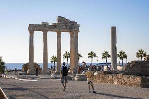 gente explorando el templo de apolo en la costa durante la puesta de sol foto