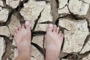 The top view of a woman's feet standing on the ground is dry from dehydration until it breaks. photo