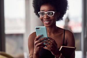 alegre mujer afroamericana con teléfono inteligente y libreta foto