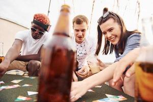 Playing card game. Group of young people in casual clothes have a party at rooftop together at daytime photo