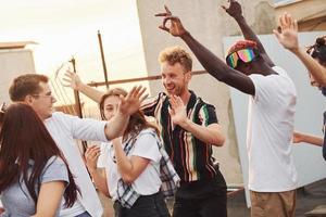 tiempo de recreo. un grupo de jóvenes con ropa informal tienen una fiesta en la azotea juntos durante el día foto