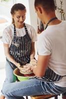 With her boyfriend or husband. Young female ceramist indoors with handmade clay product. Conception of pottery photo