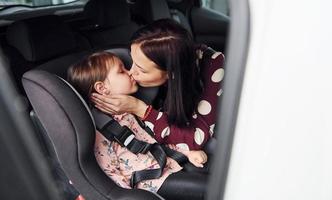 Mother with her daughter inside of modern automobile together photo